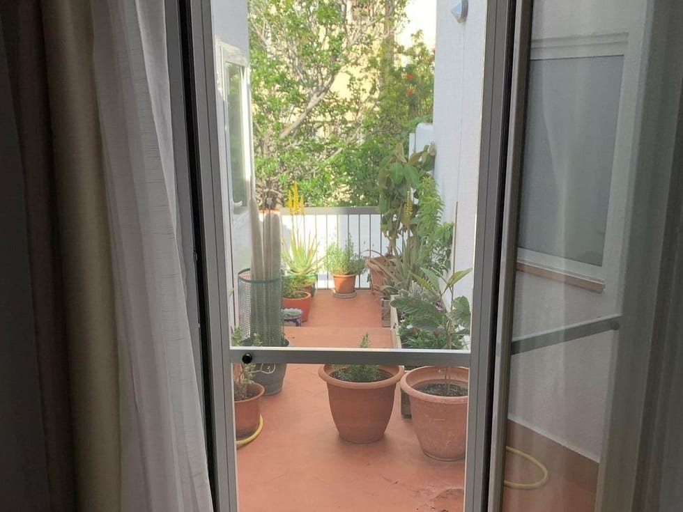 Puerta mosquitera practicable abierta en una terraza